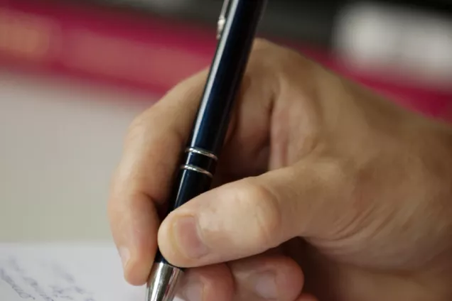 Hand holding a pen, writing. Foto.