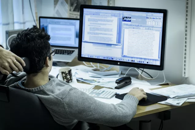 Researchers sit in front of two computer screens.