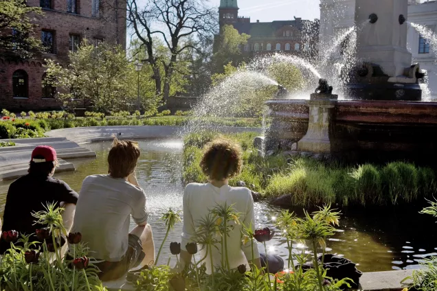 Three students are watching the fountain at Universitetsplatsen.