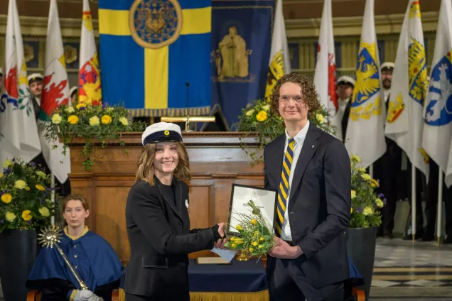 Björn Svensson receives a diploma while shaking hands with the chairman of the student union. 