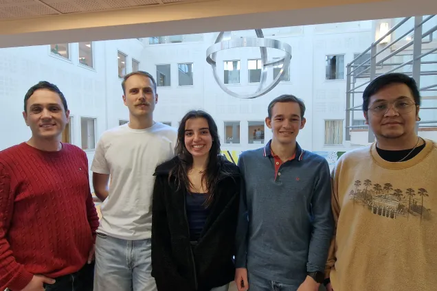 A teacher and four students standing in a row, smiling at the camera.