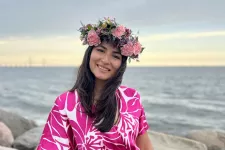 Stefany Firera is smiling at the camera. She has a big flower crown on her head. The Öresund bridge is in the background