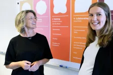 Career coaches Pernilla Thellmark and Stina Vikingsson, standing in front of a whiteboard with text on. Photo.